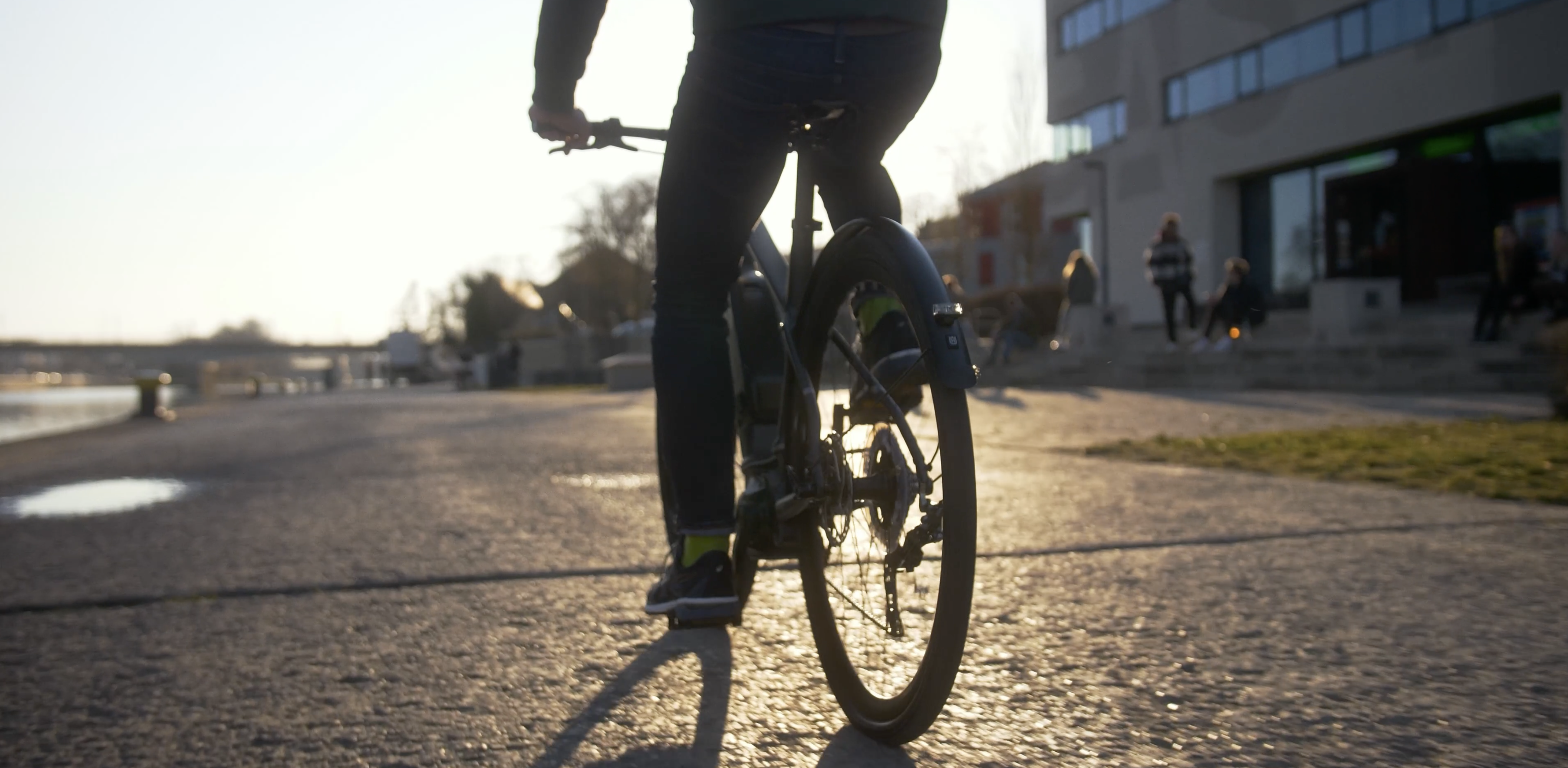 Ein lachendes Paar steht neben ihren Fahrrädern vor einem historischen Steingebäude. Beide tragen Fahrradhelme, die sie locker in der Hand halten, während sie sich anschauen und unterhalten.