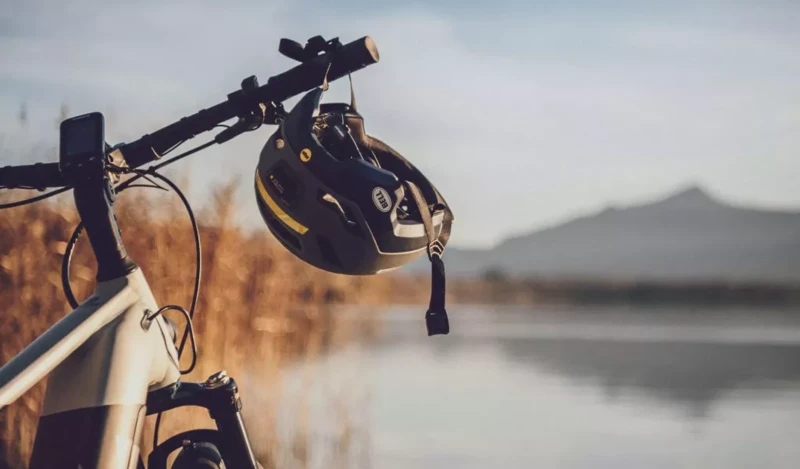 Ein Fahrrad steht am Ufer eines Sees, ein Helm hängt am Lenker.