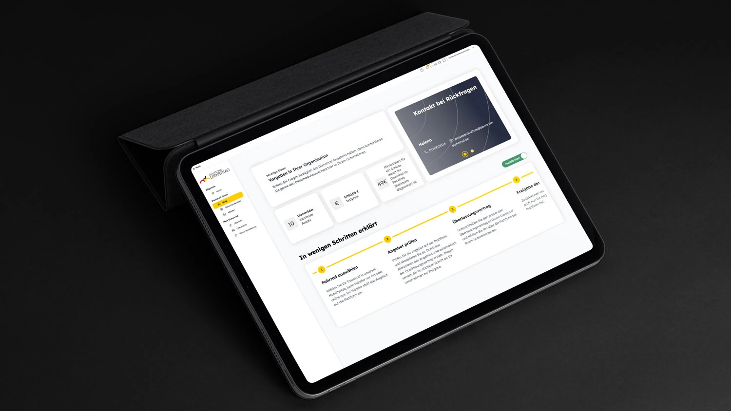 Ein Tablet mit einem geöffneten Dashboard auf dem Bildschirm, das Informationen und eine Schritt-für-Schritt-Anleitung für Fahrradleasing anzeigt. Das Tablet liegt in einem schwarzen Case auf einer dunklen Oberfläche und zeigt eine klare, strukturierte Benutzeroberfläche mit Text und grafischen Elementen.